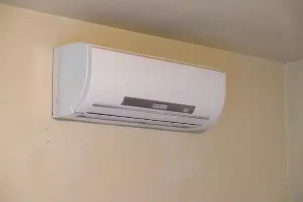 A white wall-mounted split air conditioner unit installed high on a light-colored wall, with vents and control panel visible on the front—expertly serviced by an HVAC Contractor North Attleboro, MA.